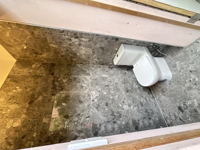 Renovated toilet with stone-look floor-to-ceiling tiles