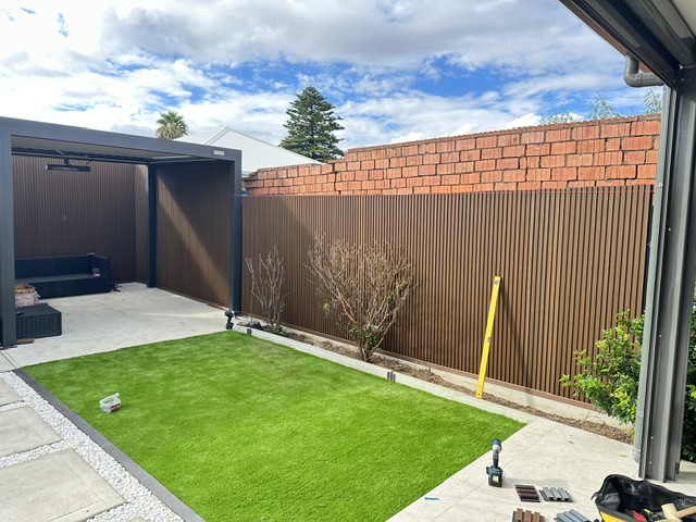 Same backyard after — pergola, slat fencing and fresh turf